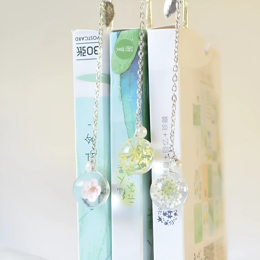 Dried flower sealed inside a rectangular silver metal bookmark with a hole at the top.