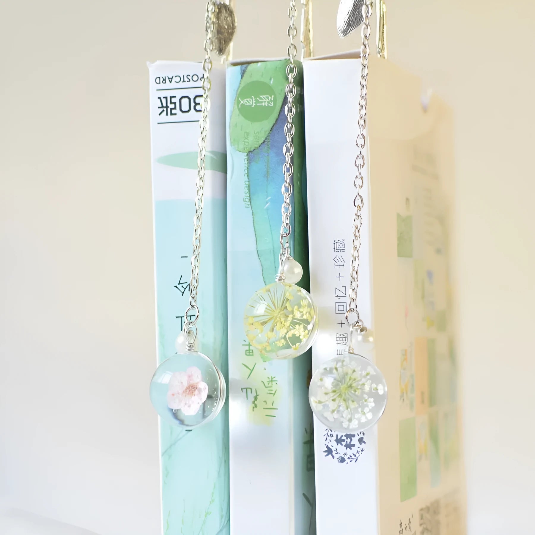 Dried flower sealed inside a rectangular silver metal bookmark with a hole at the top.