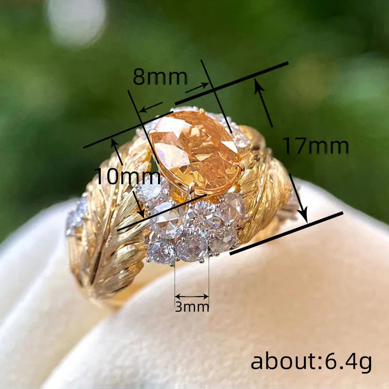 Gold-coloured women's ring with embossed feather pattern and yellow zircon stone inlay on copper base
