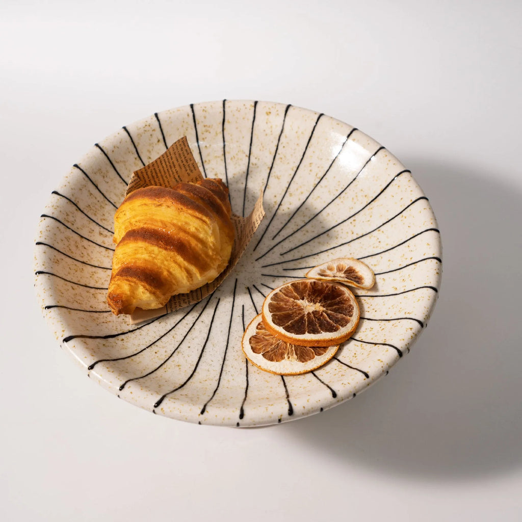 Black and white striped synthetic resin fruit plate on a wooden table.