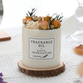 Decorative dried flower aromatherapy candle on a wooden chip base, shown with a gift box.