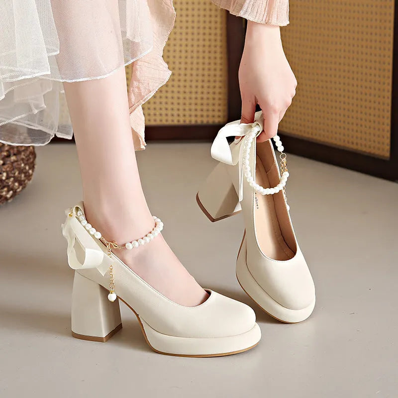 Women's beige Mary Jane shoes with chunky heel and ankle strap buckle on a wooden floor.