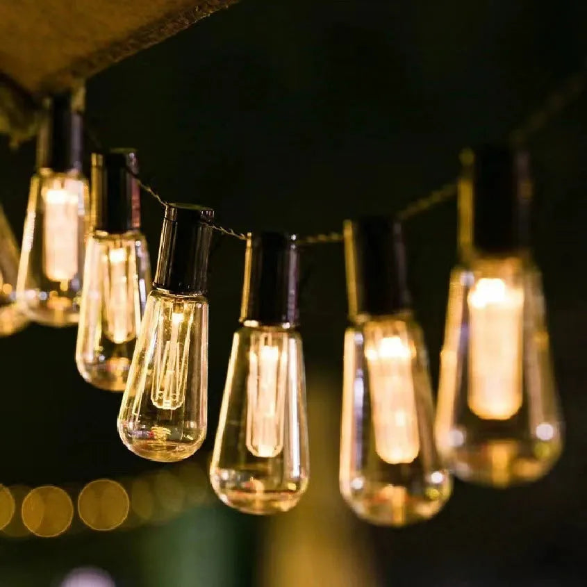 Retro outdoor string lights with infusion bottle-shaped bulbs in garden setting