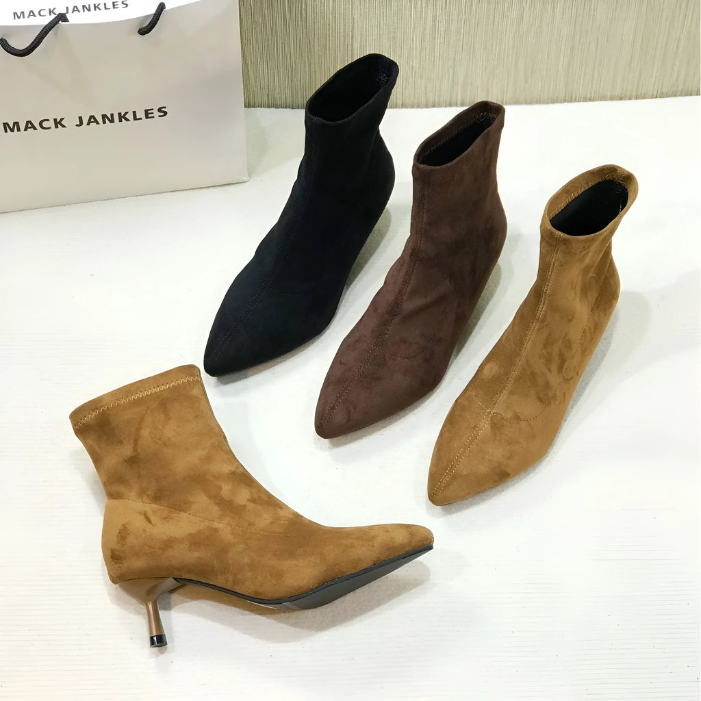 Black pointed toe women's ankle boots with a stiletto heel on a plain background.