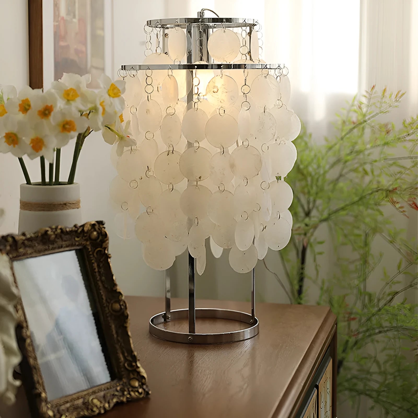 Modern shell-shaped bedside table lamp in chrome metal finish on a wooden surface.
