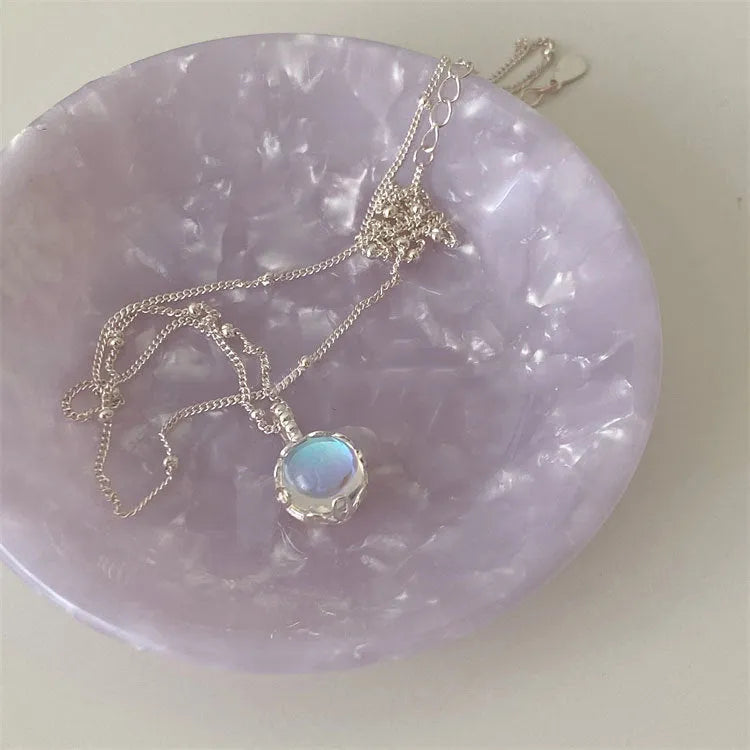 Women's silver necklace with large round geometric stone pendant on a curb chain.
