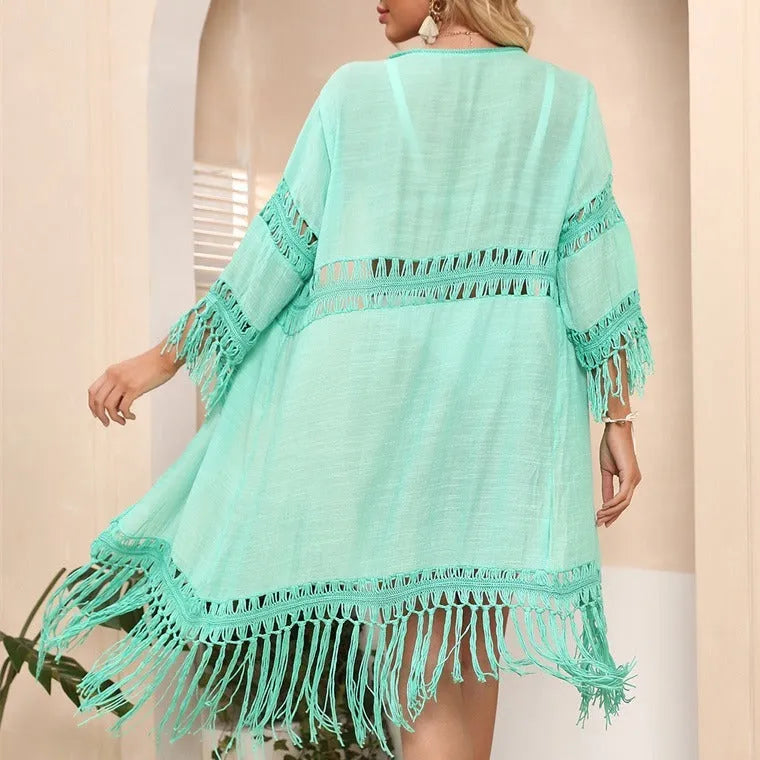 Women's hand-crocheted acrylic beach cardigan in water green with tassel details, laid flat.
