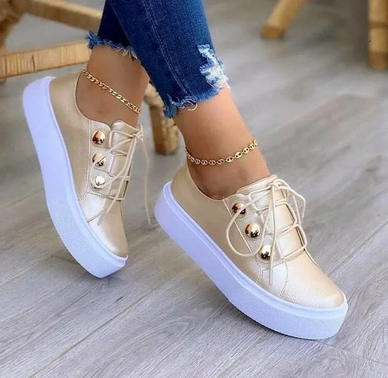 Women's white lace-up flats sneakers with decorative silver rivets and front-tie lacing.
