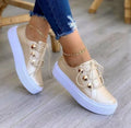 Women's white lace-up flats sneakers with decorative silver rivets and front-tie lacing.
