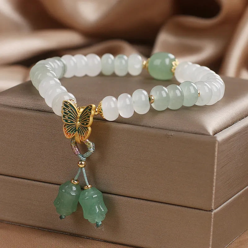 Green crystal women's bracelet with abacus beads, a butterfly tassel, pearls, and rhinestones.