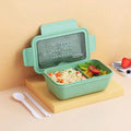Green partitioned bento box with four food compartments showing Nordic design