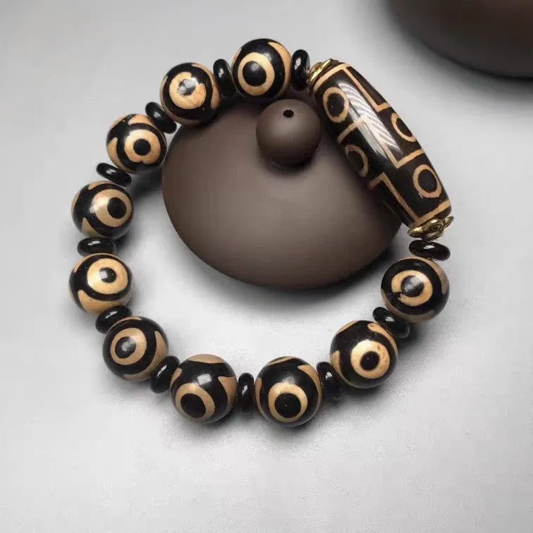 Distressed agate Tibet bead bracelet with three-eye motifs and multiple traditional bead styles on wrist