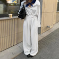 White striped wide-leg women's trousers with side zip, laid flat to show loose fit and pattern.