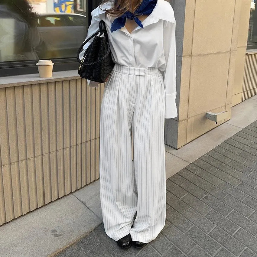 White striped wide-leg women's trousers with side zip, laid flat to show loose fit and pattern.