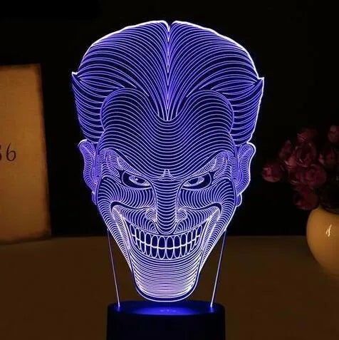A 3D LED table lamp with a colourful acrylic panel on a square base, showing multiple colour options.