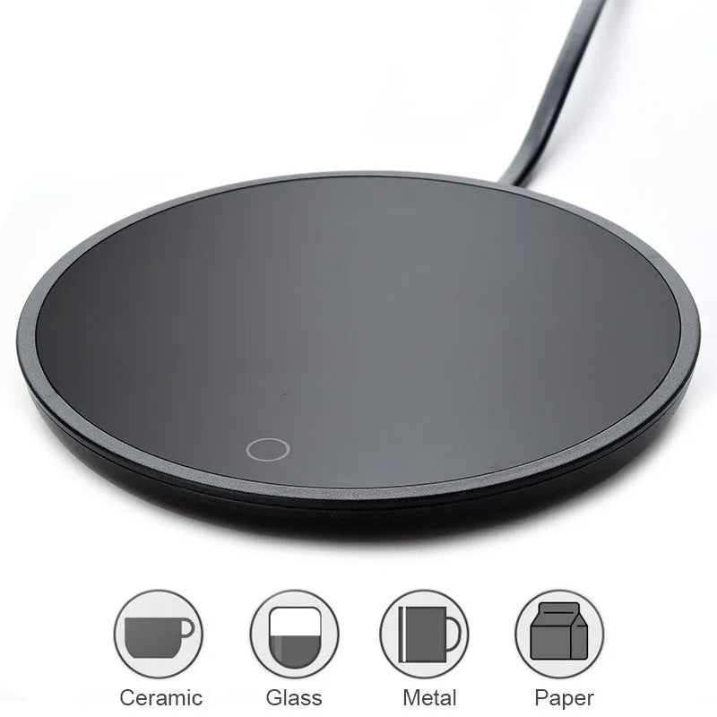 Black coffee mug warmer with temperature switch on desk next to ceramic cup