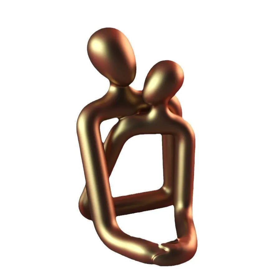 Modern loving couple resin statue in gold or milky white finish on a wooden desk.