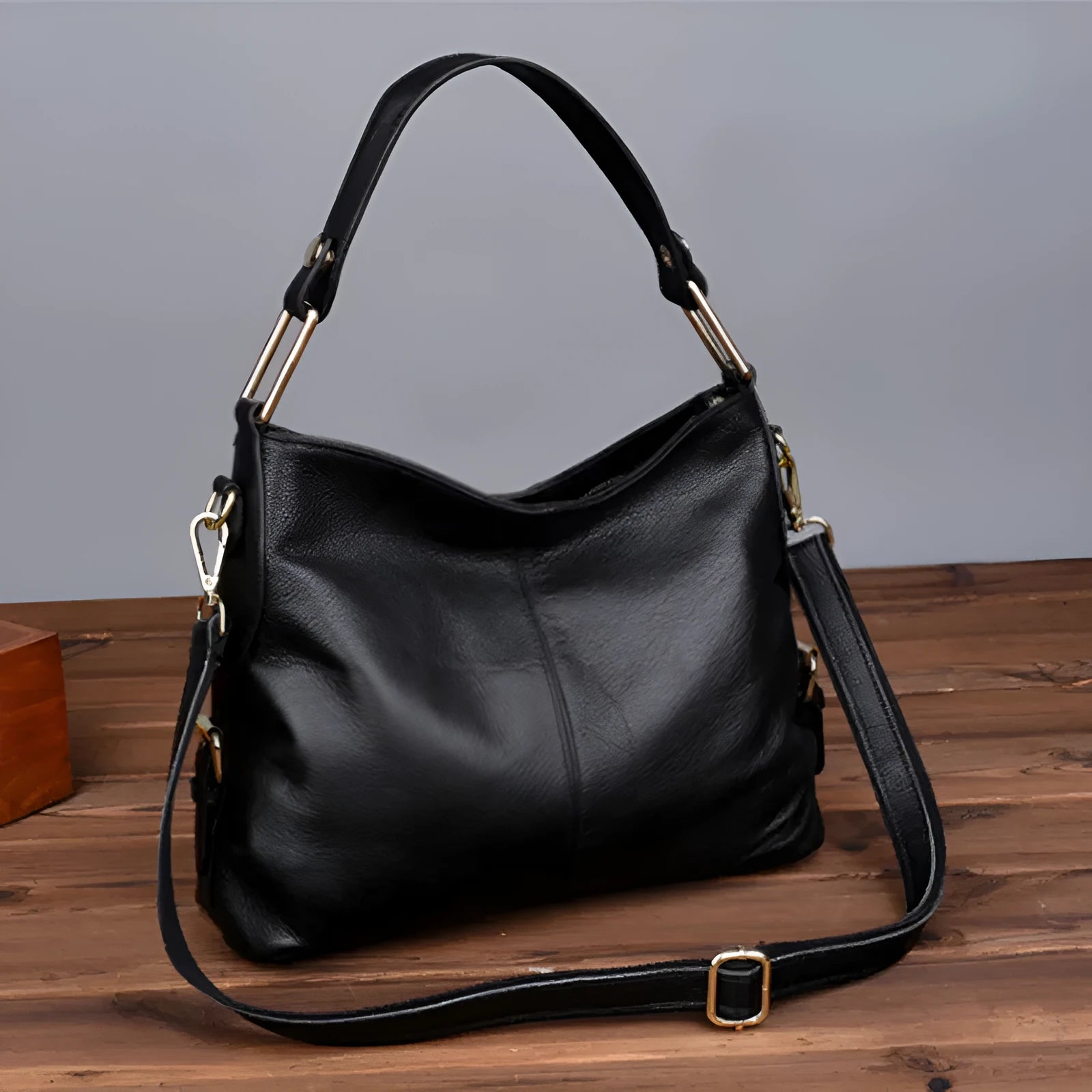 Genuine leather vertical square crossbody bag in black, showing front sandwich pocket and sewing line details.