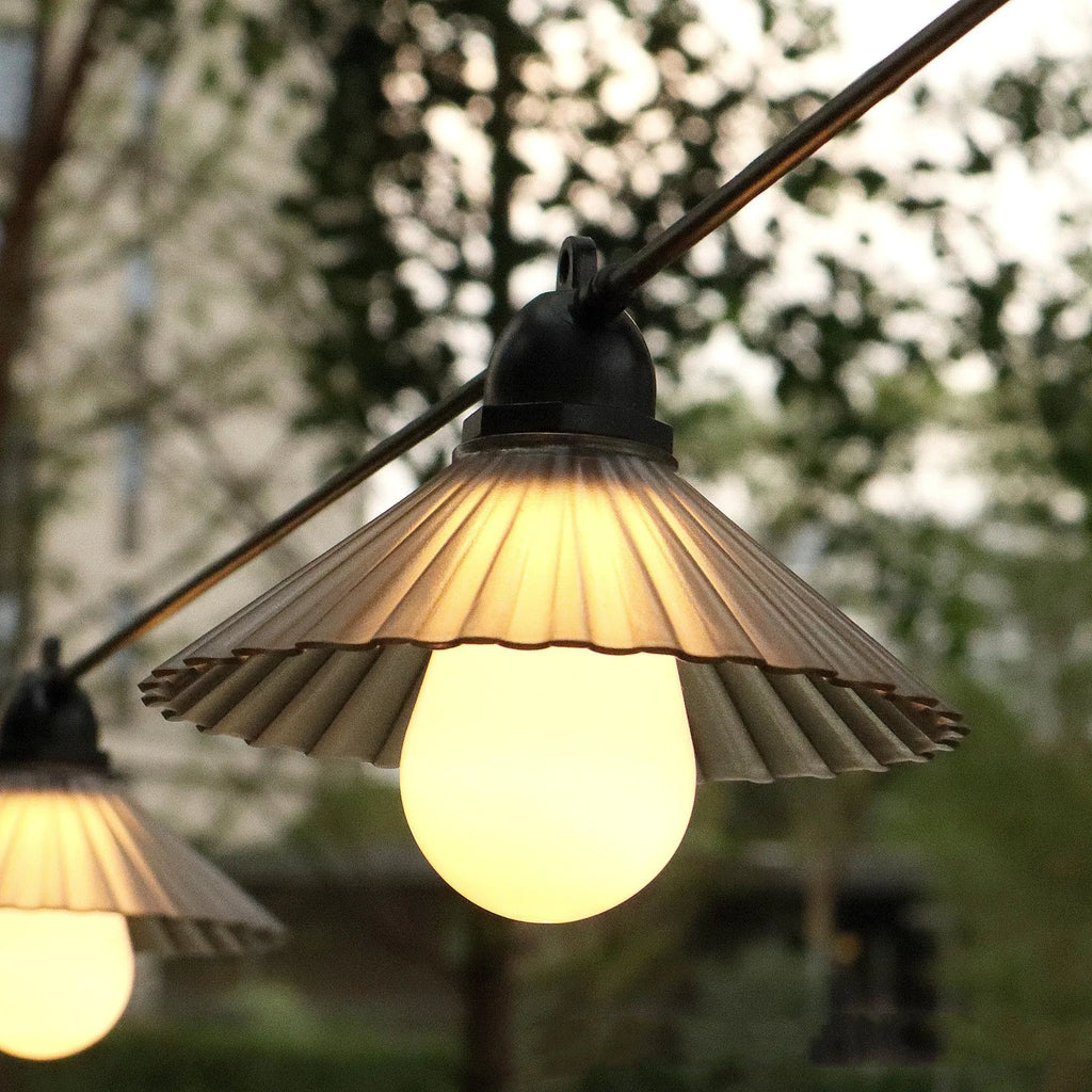Outdoor LED string lights with flower-shaped bulbs hanging in a garden setting.