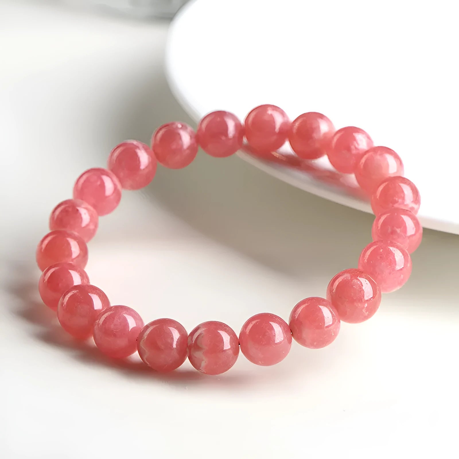 Women's geometric red rhodochrosite crystal bracelet with a longevity lock clasp on a wrist.