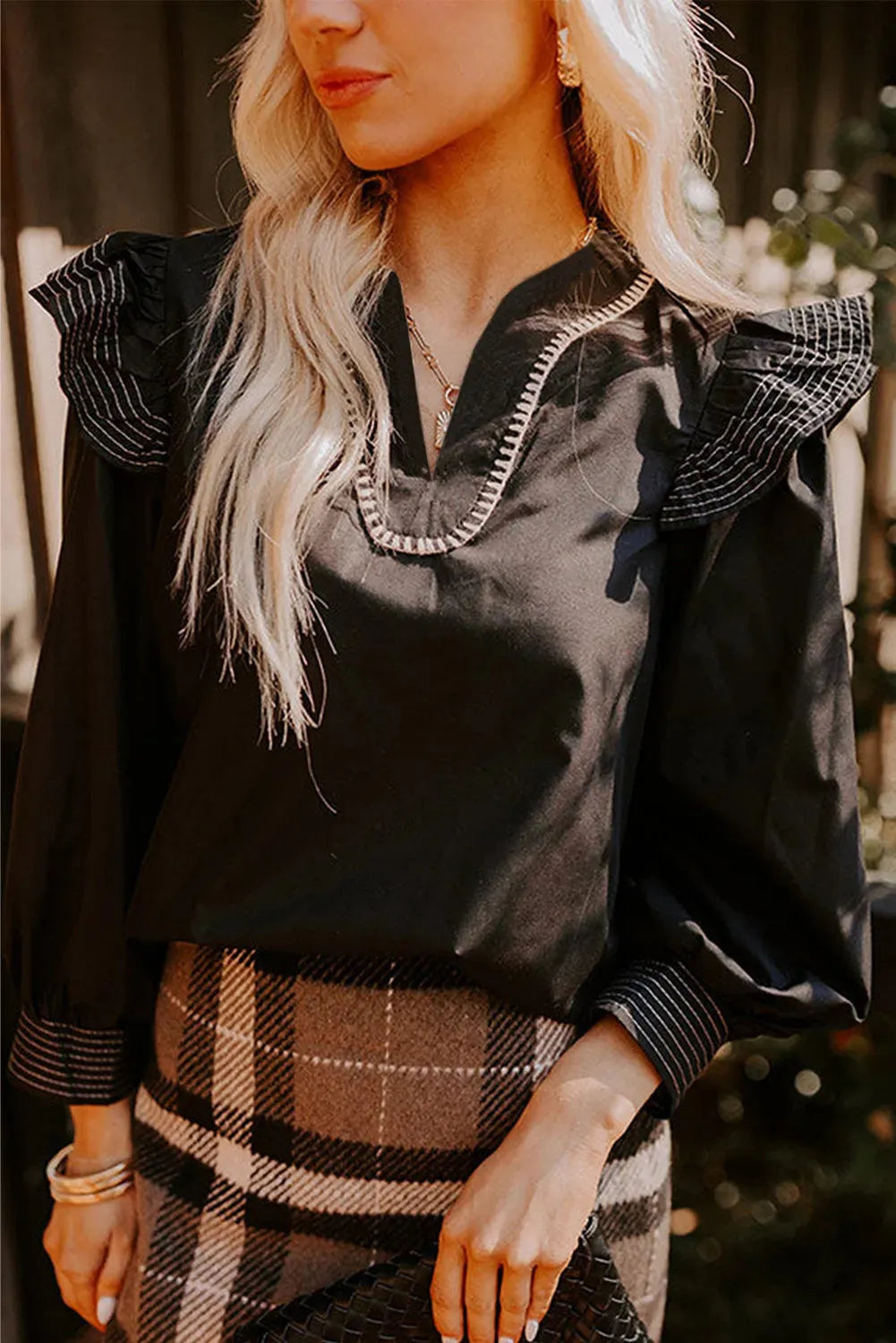 Black V-neck blouse with contrast stitching on ruffle long sleeves
