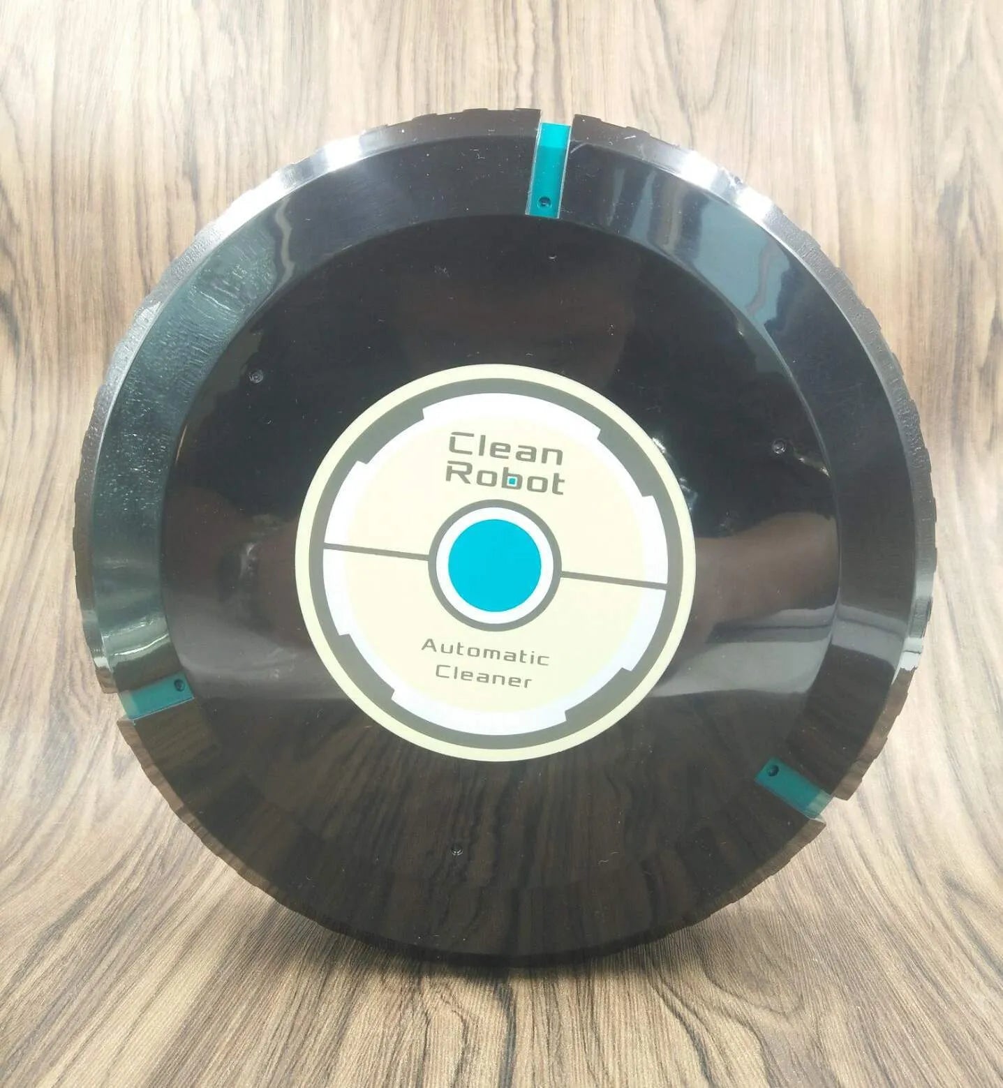 Black and white AC Sweeping Robot automatic vacuum cleaner on a hardwood floor.