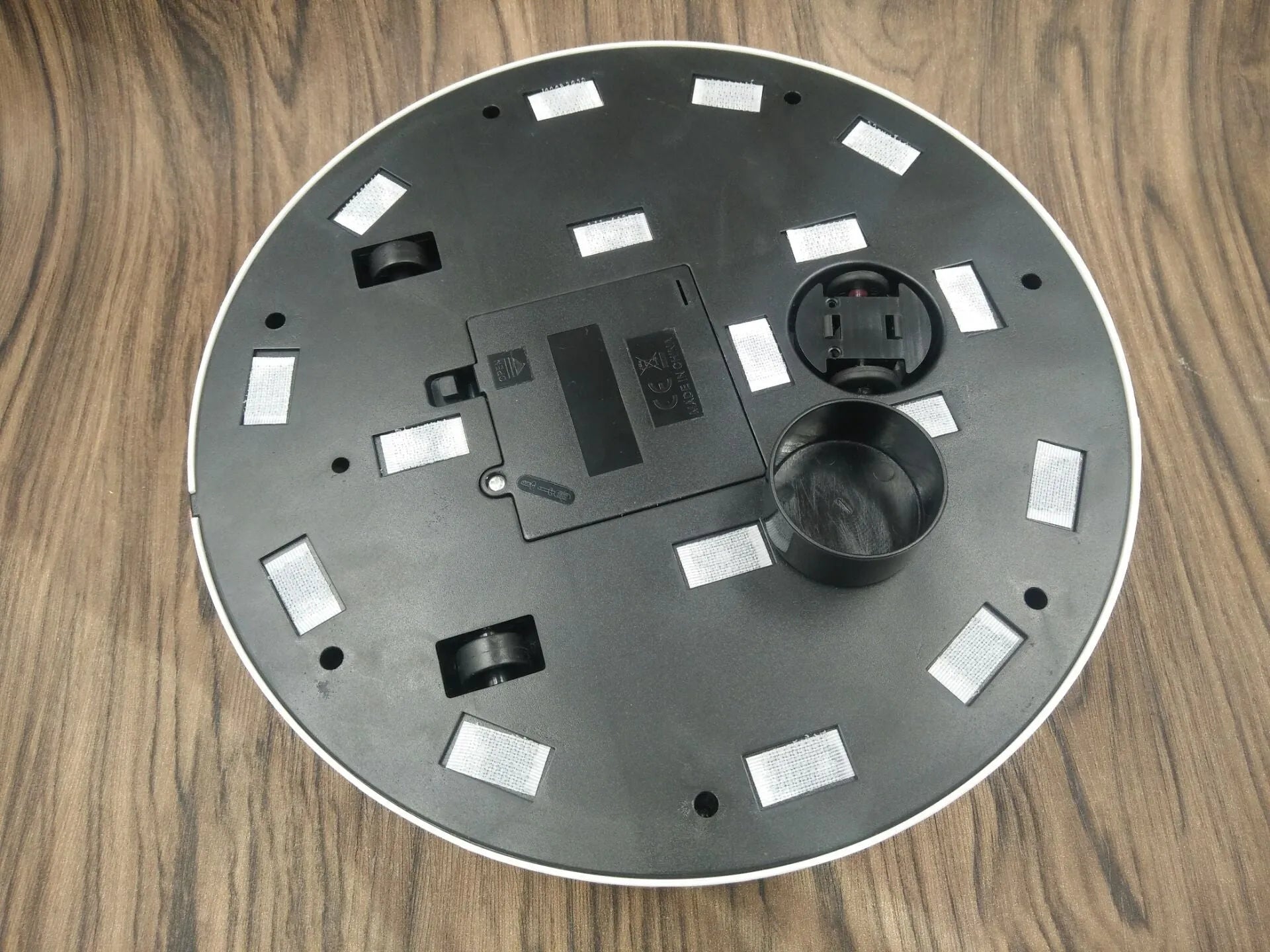 Black and white AC Sweeping Robot automatic vacuum cleaner on a hardwood floor.