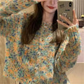 Pink and green retro rainbow patterned knitted cardigan sweater on a hanger.