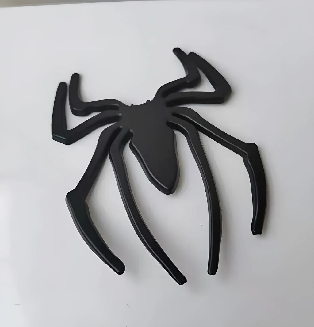 Three-dimensional metal spider car bumper sticker in zinc alloy, shown in gold colour.