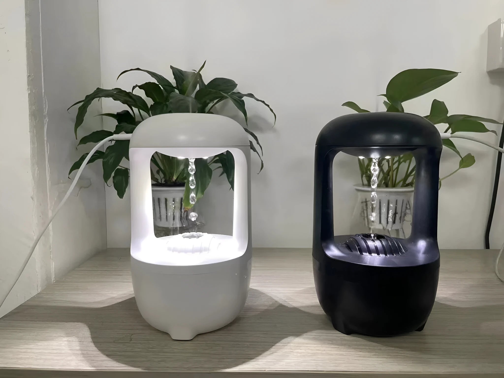 White anti-gravity humidifier with floating water droplet on a desk next to a USB cable