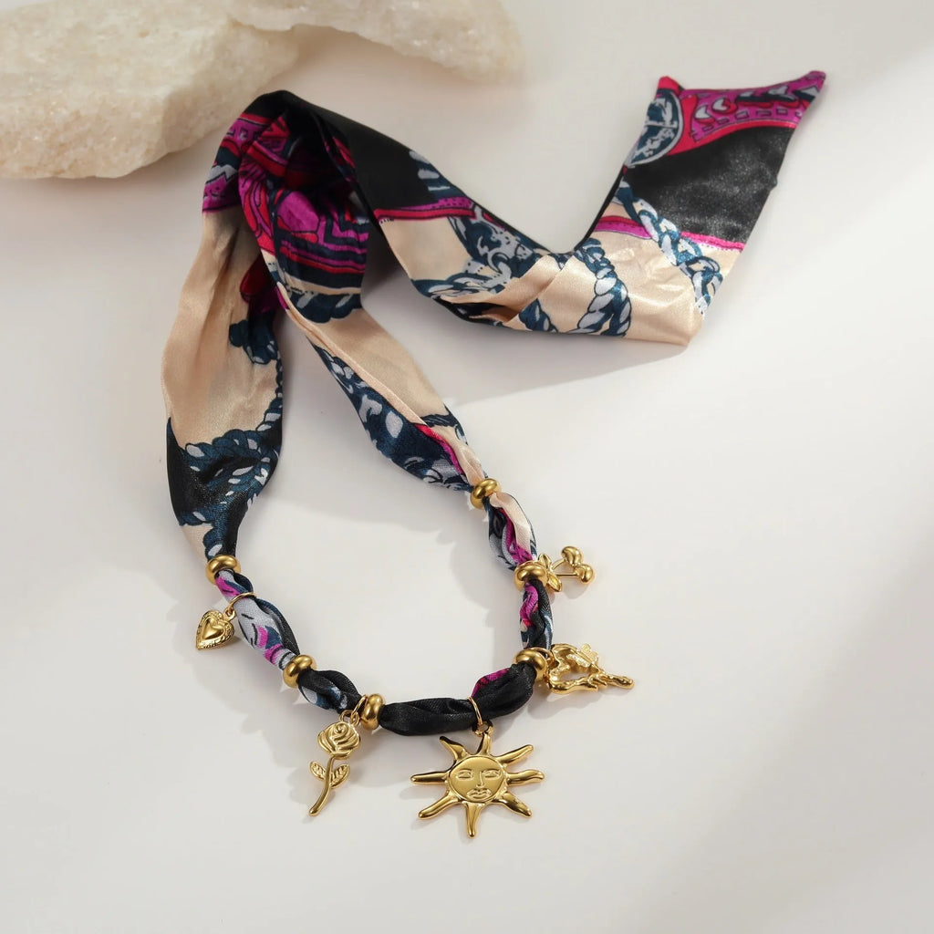 Geometric sun pendant on a gold chain, shown as both a women's necklace and bracelet on a grey background.