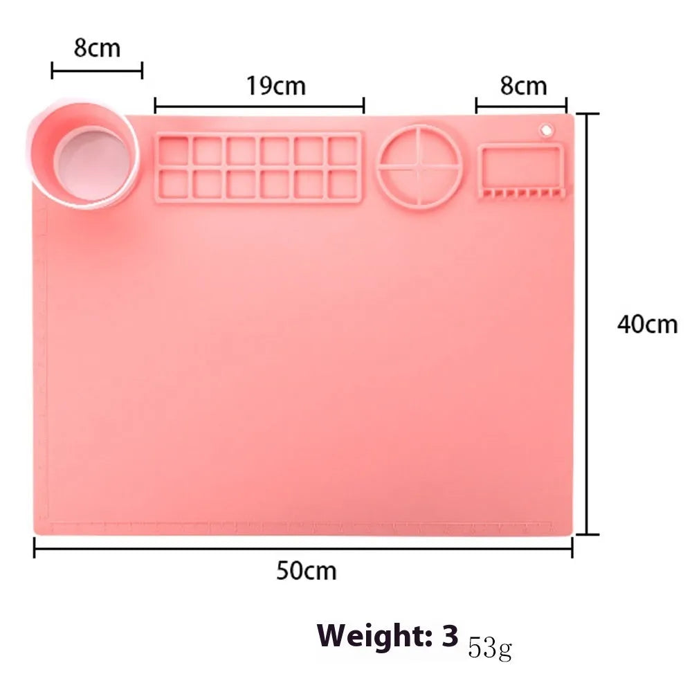 Light blue silicone painting mat with two recessed bowls for holding paint, placed on a wooden table.