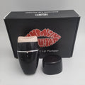 Black and white electric lip plumper device with silicone tip and USB cable on a plain background.
