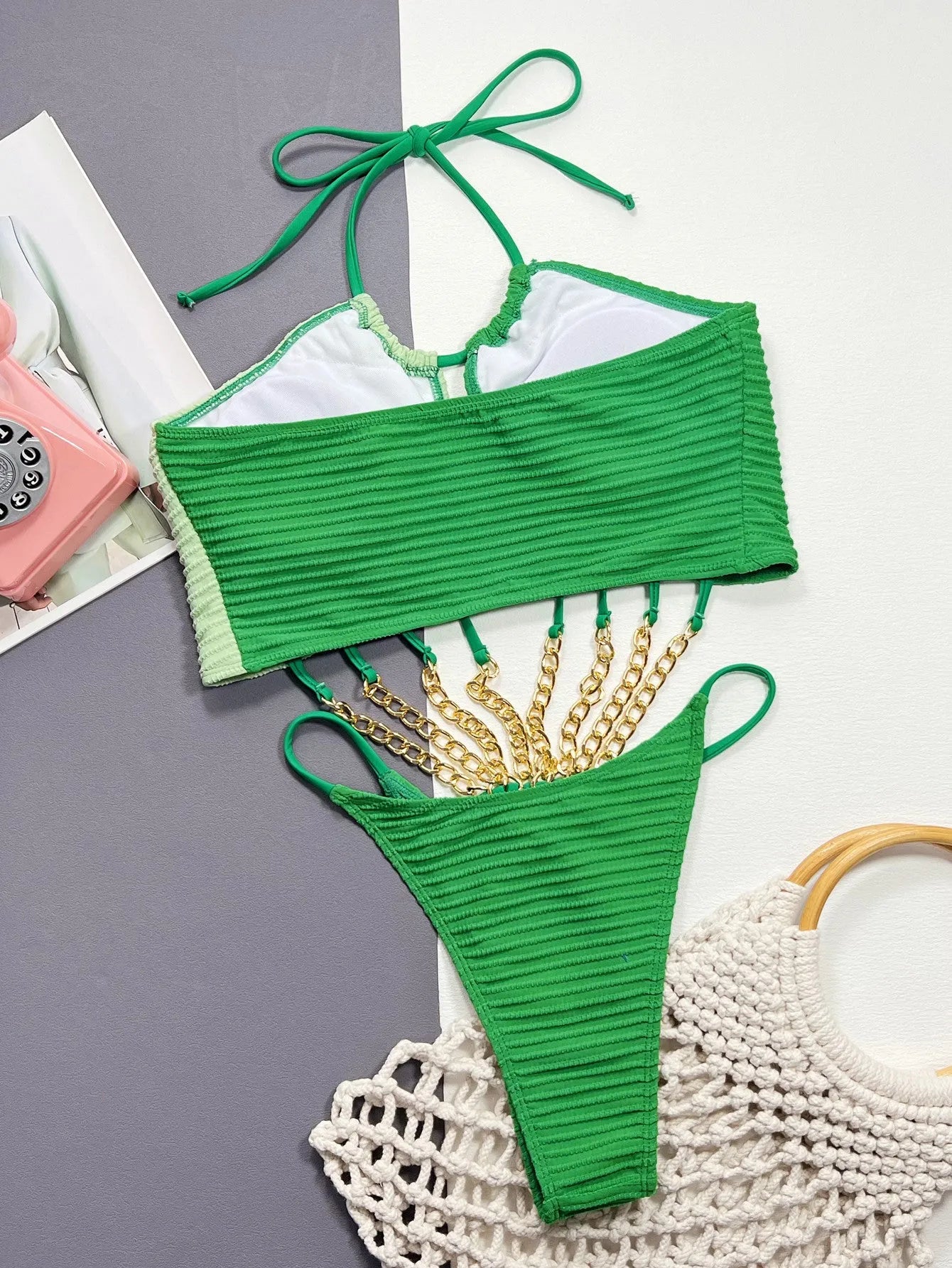 Green women's one-piece swimsuit with a hollow design on a solid colour background.