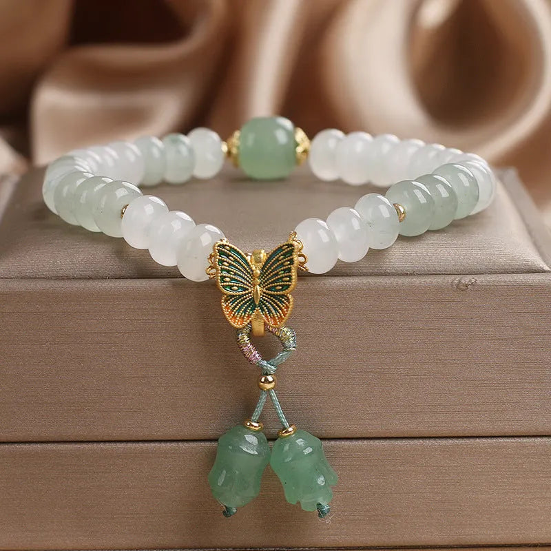 Green crystal women's bracelet with abacus beads, a butterfly tassel, pearls, and rhinestones.