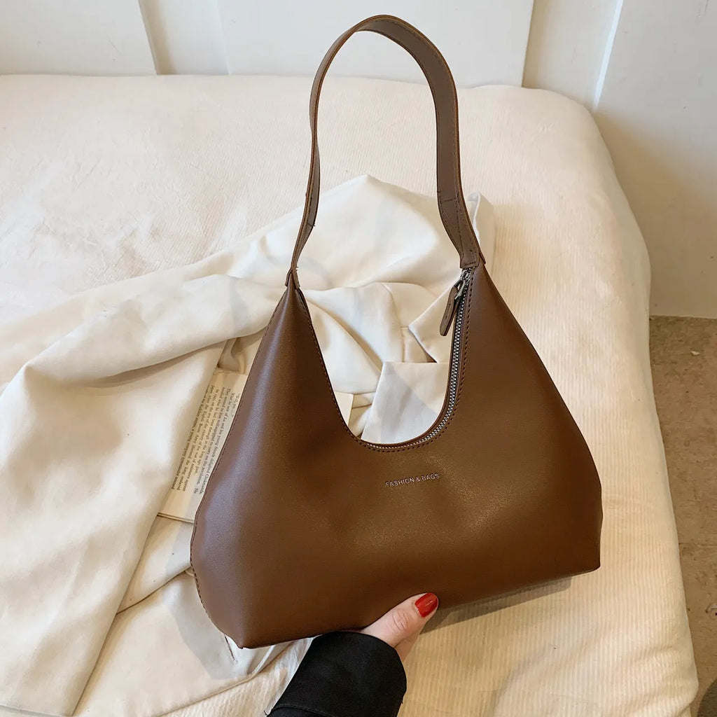 Brown retro PU leather shoulder handbag with a single strap and pillow-shaped design on a plain background.