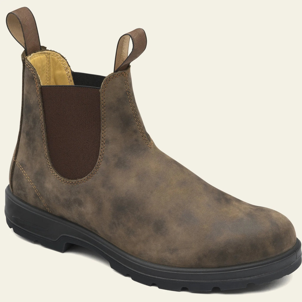 Vintage brown Chelsea boots with frosted finish and car suture detailing on a wooden floor.