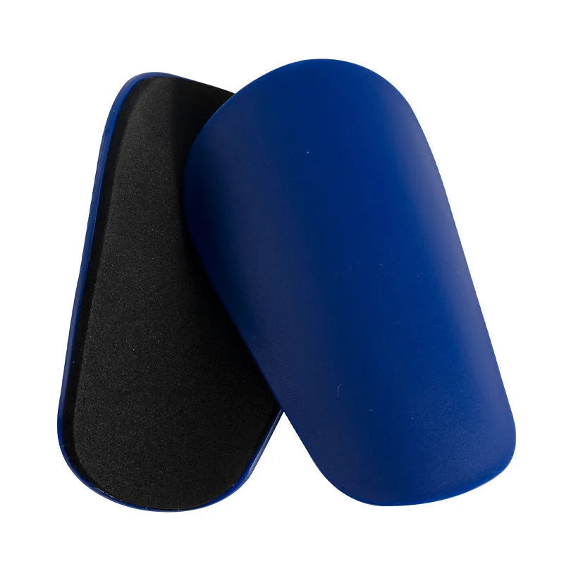 Pair of PU mini shin guards in black with adjustable straps, shown on a leg.
