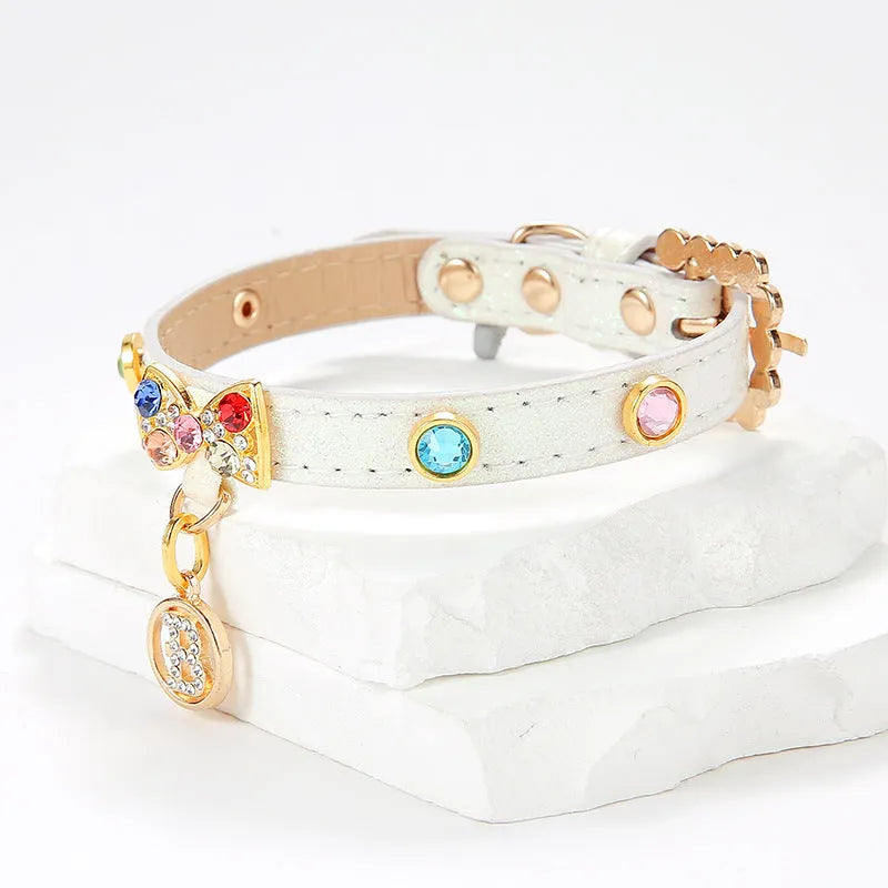 White PU leather cat collar with diamond alloy bow displayed on a surface, showing buckle and adjustable length
