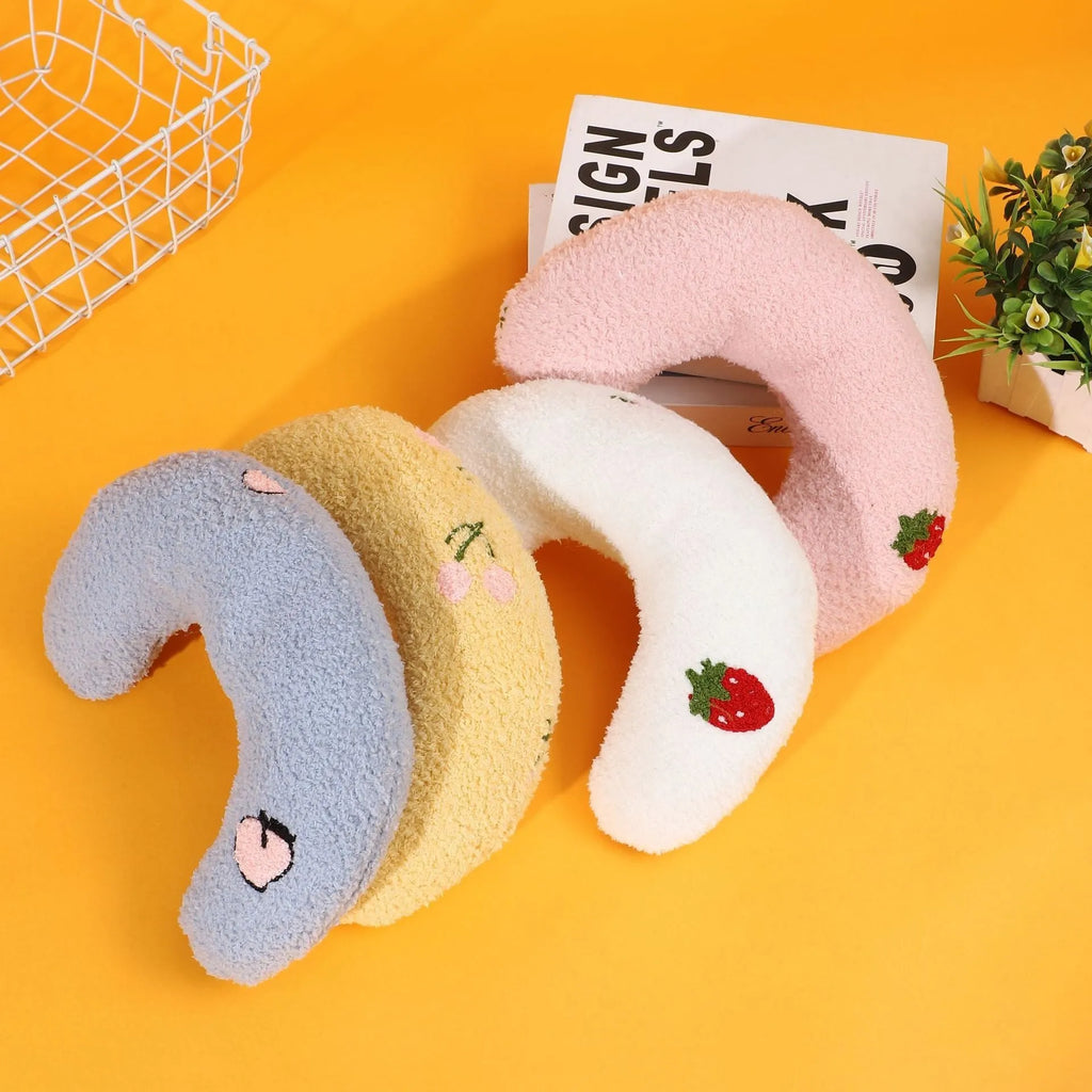 Blue U-shaped half moon cartoon pillow for cats on a wooden floor.