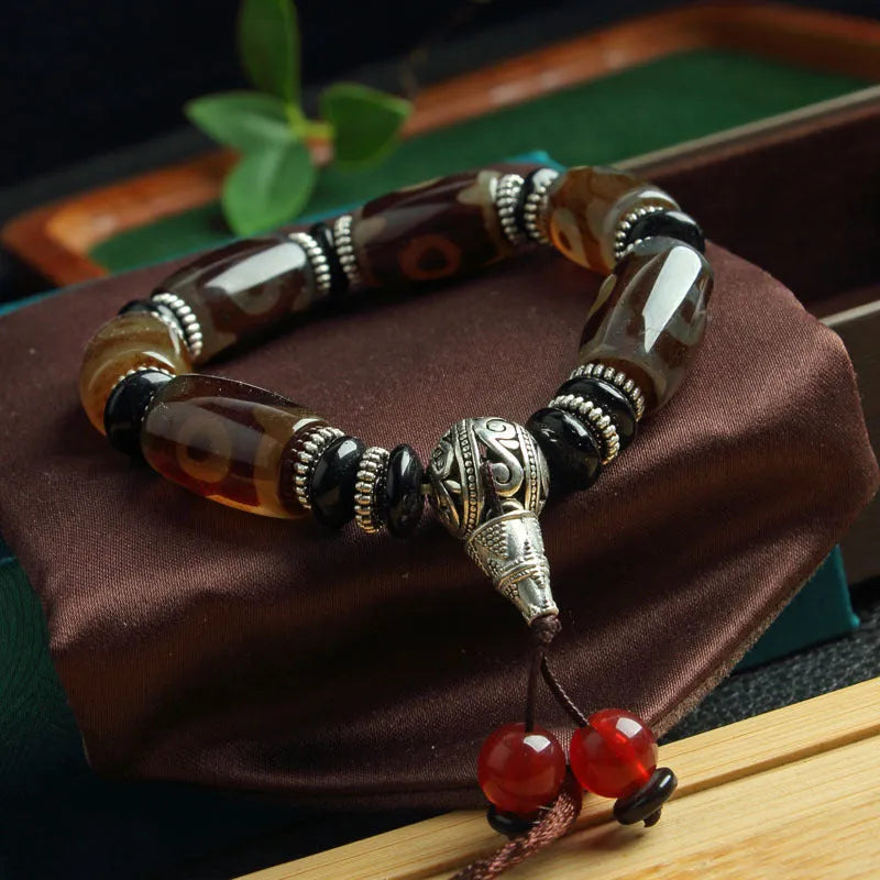 Distressed agate Tibet bead bracelet with three-eye motifs and multiple traditional bead styles on wrist