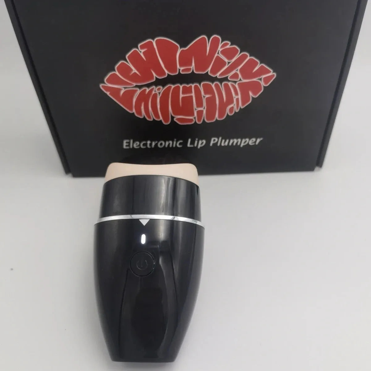 Black and white electric lip plumper device with silicone tip and USB cable on a plain background.