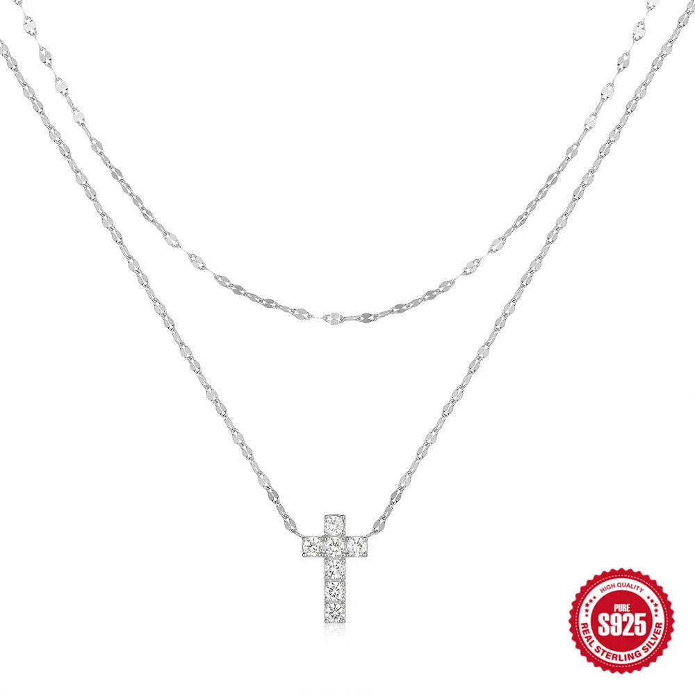 Close-up of a double-layer sterling silver cross pendant on a clavicle chain, available in gold and white gold finishes.
