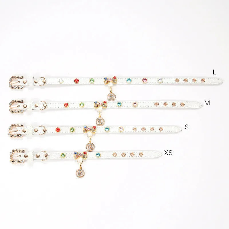 White PU leather cat collar with diamond alloy bow displayed on a surface, showing buckle and adjustable length