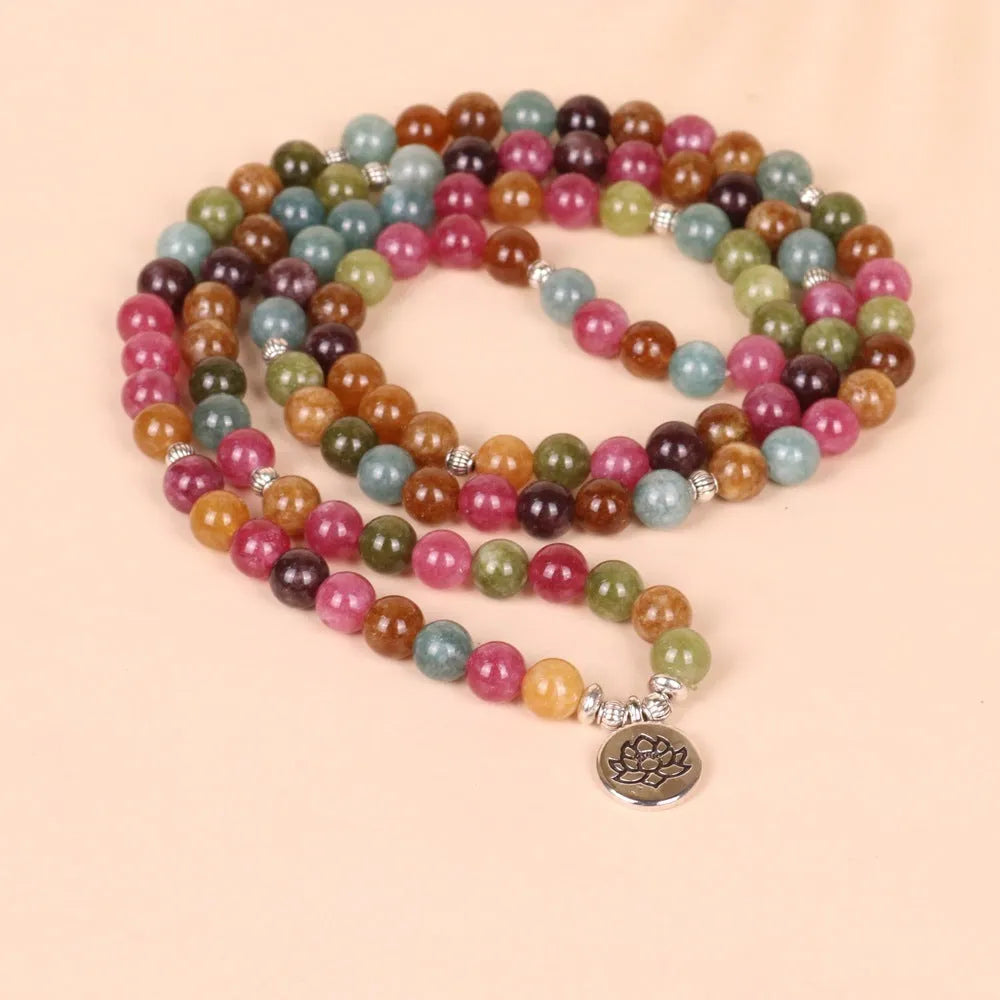 Multi-layer beaded bracelet with 108 tourmaline beads, lotus charm, and alloy clasp on a wrist.