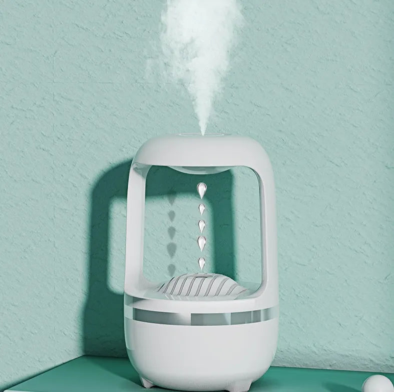 White anti-gravity humidifier with floating water droplet on a desk next to a USB cable