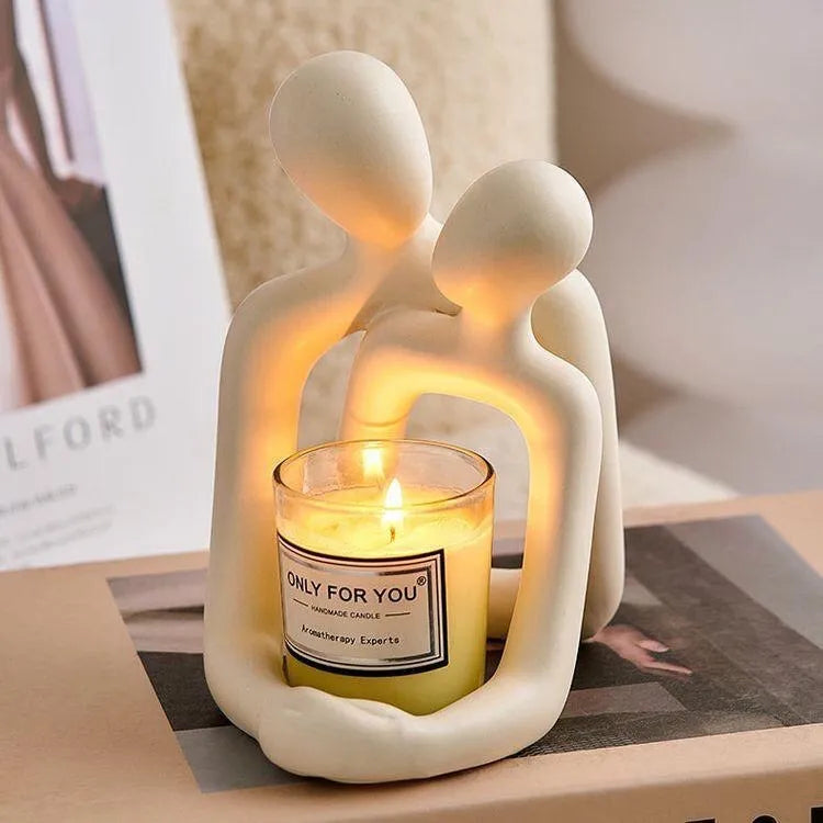 Modern loving couple resin statue in gold or milky white finish on a wooden desk.
