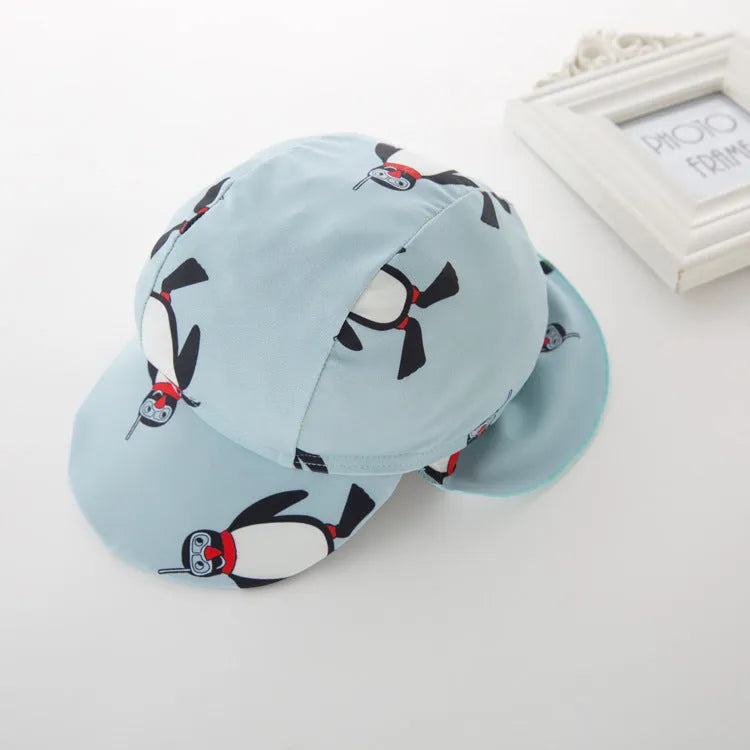 Boy's blue penguin print long sleeve swimsuit top and shorts with matching swimming cap.