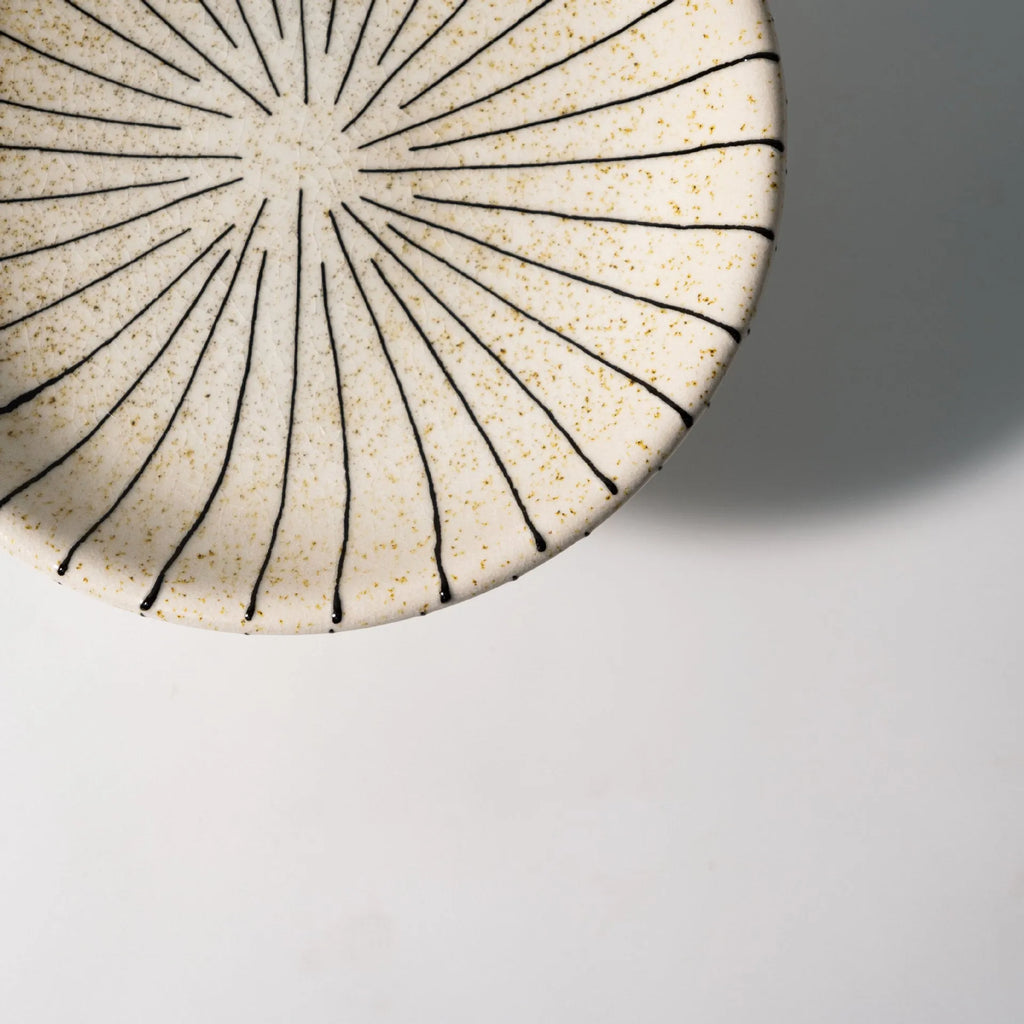 Black and white striped synthetic resin fruit plate on a wooden table.