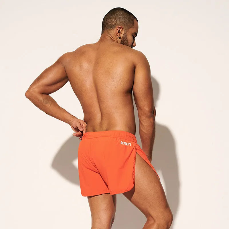 Men's loose orange polyester beach shorts on a hanger against a neutral background